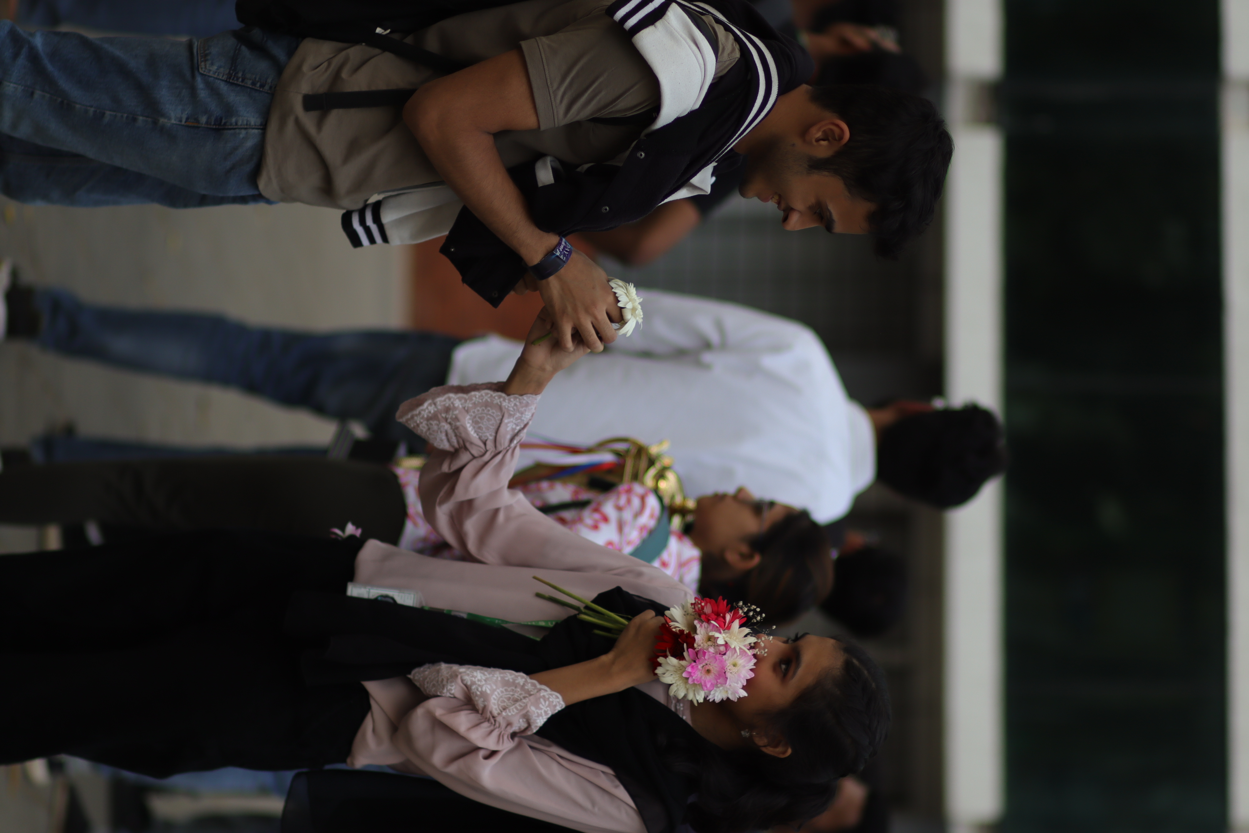 A young man offering a flower to a young woman