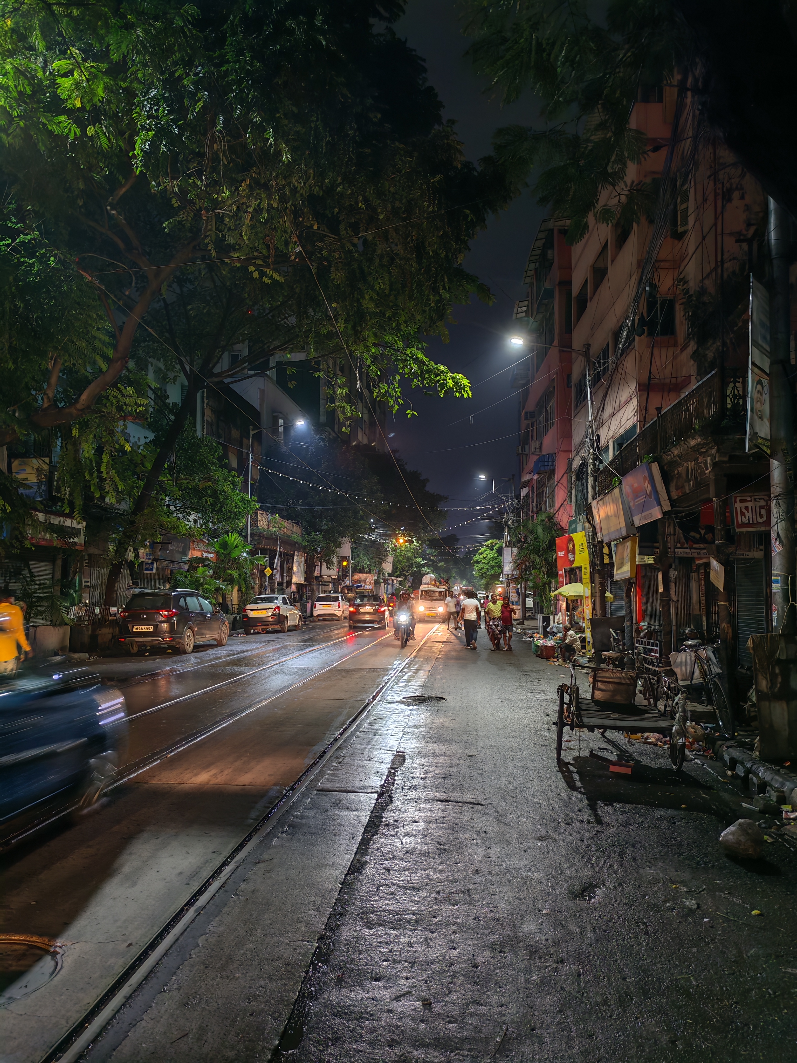 A rain-darkened Kolkata street lit by evening traffic