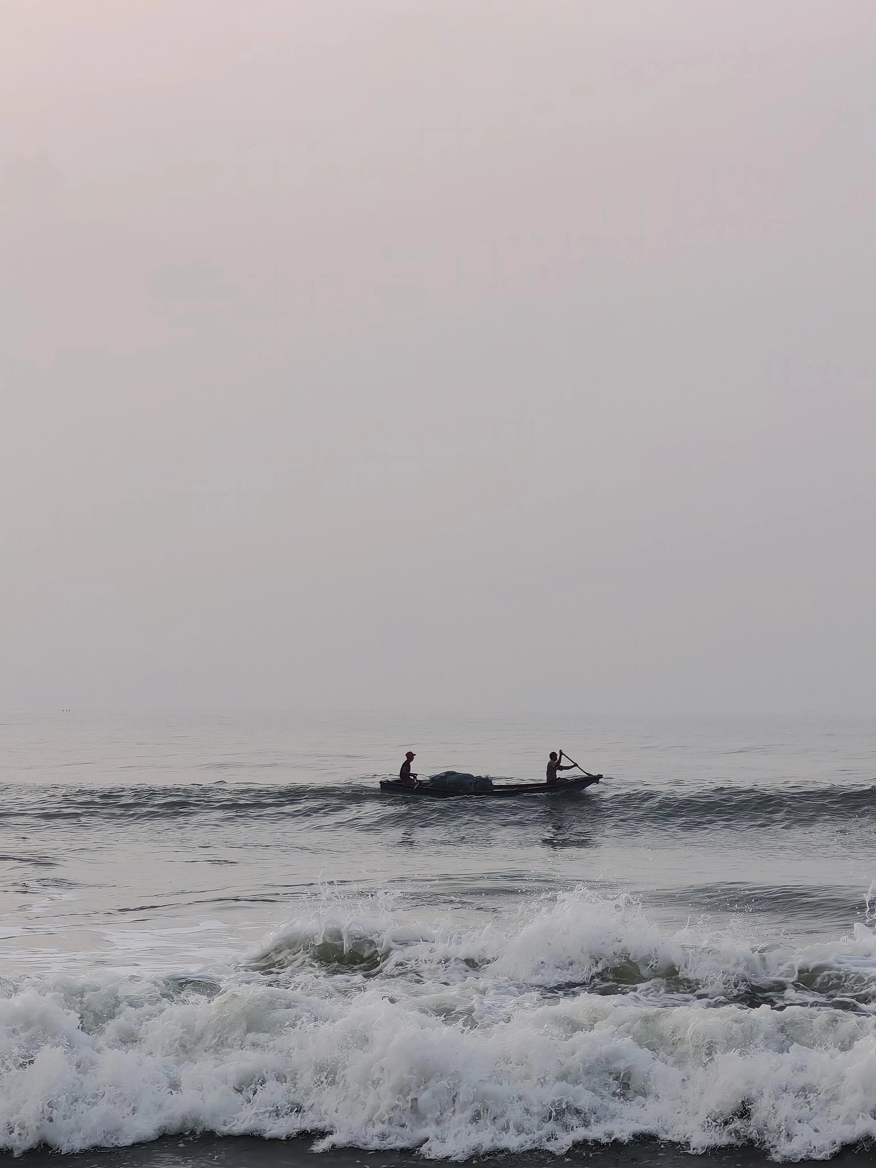 Two people crossing rolling water in a small boat