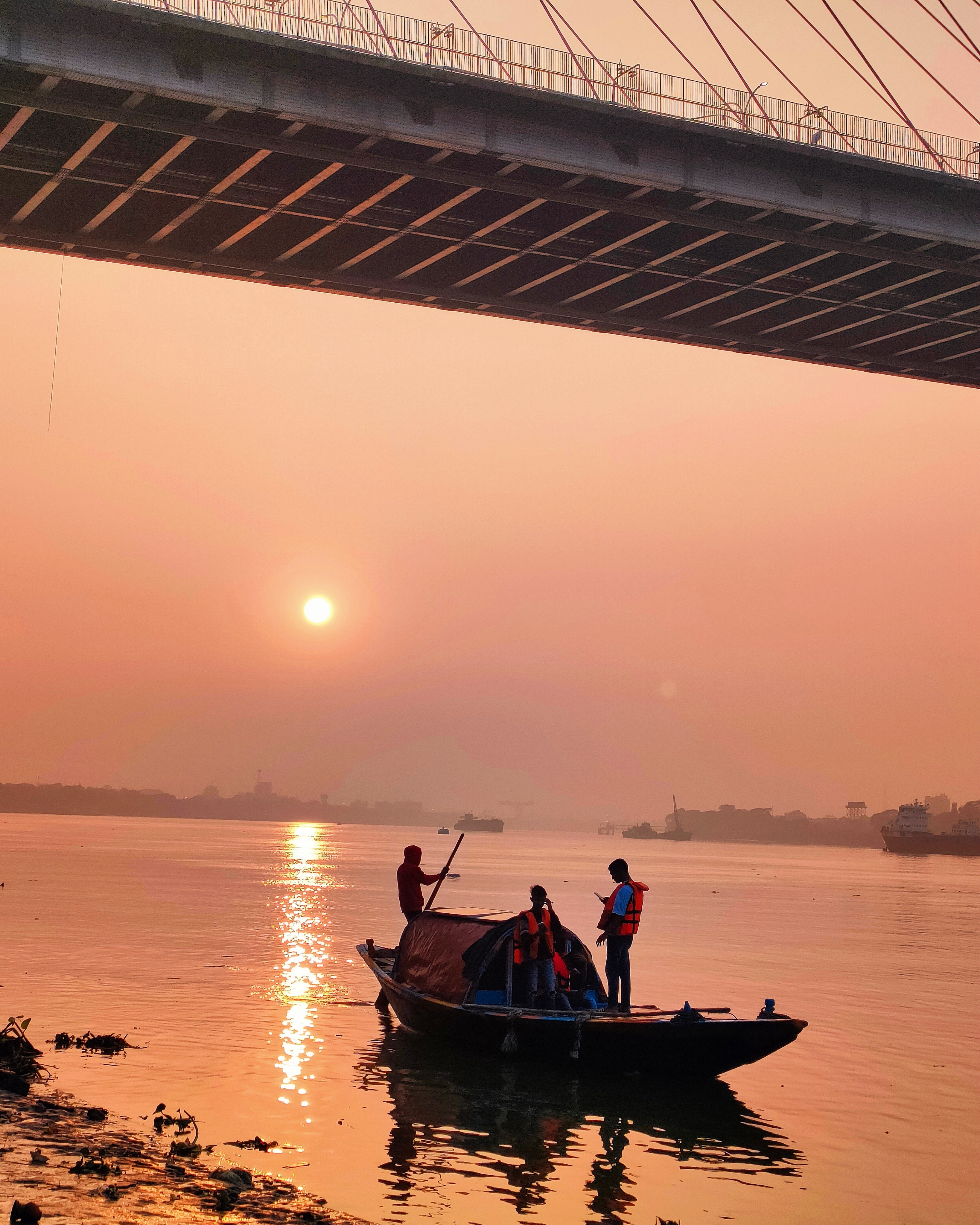 A small boat crossing the Hooghly River at sunrise