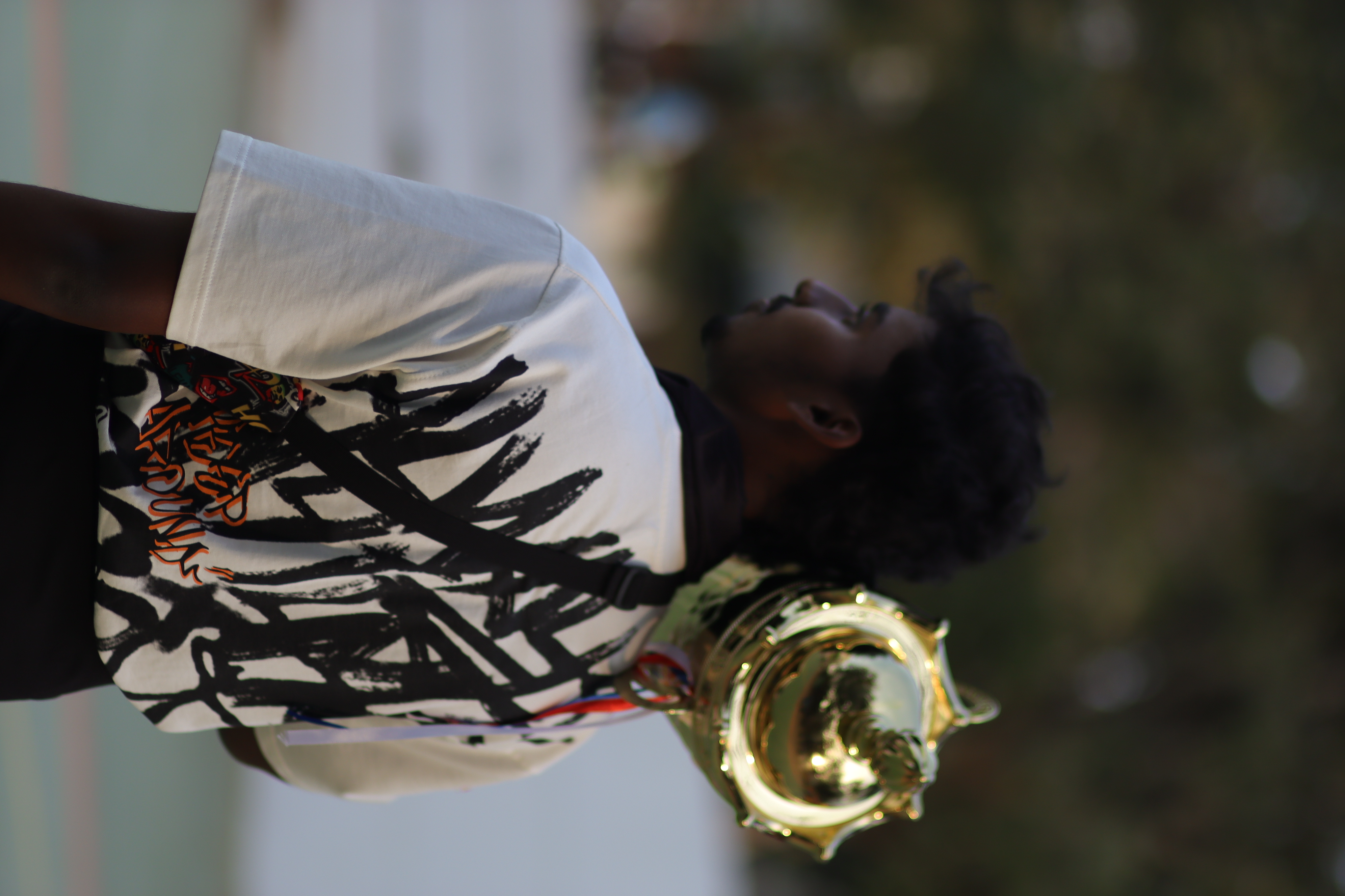 A young man carrying a brass trophy over his shoulder